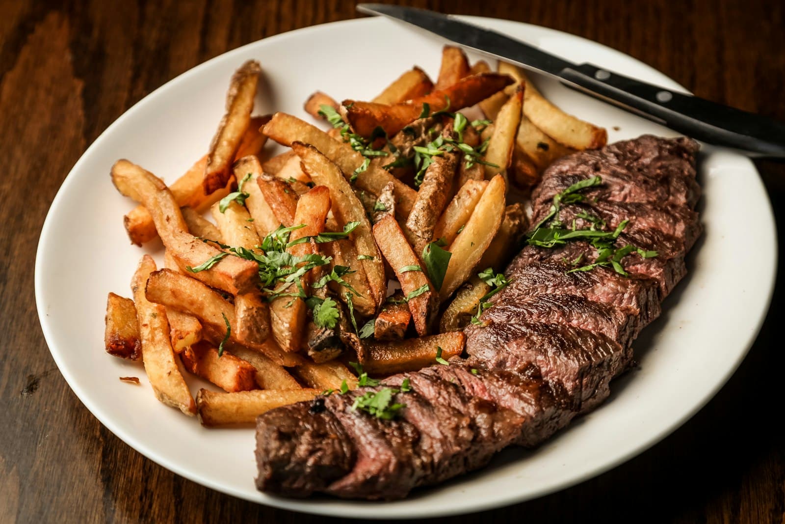 Plat servi dans un bistrot, steak frites sur table en bois